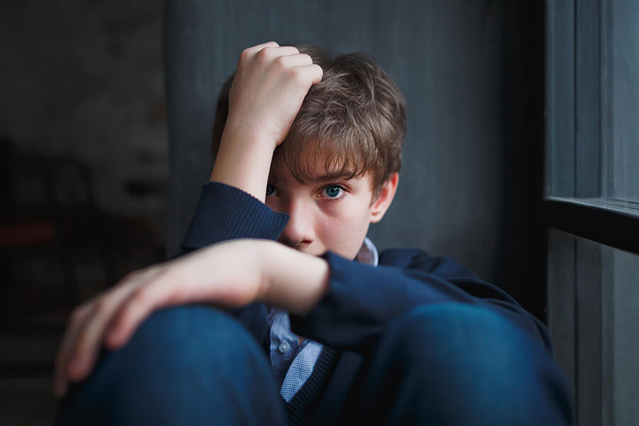 teenage boy hunched on floor looking forward